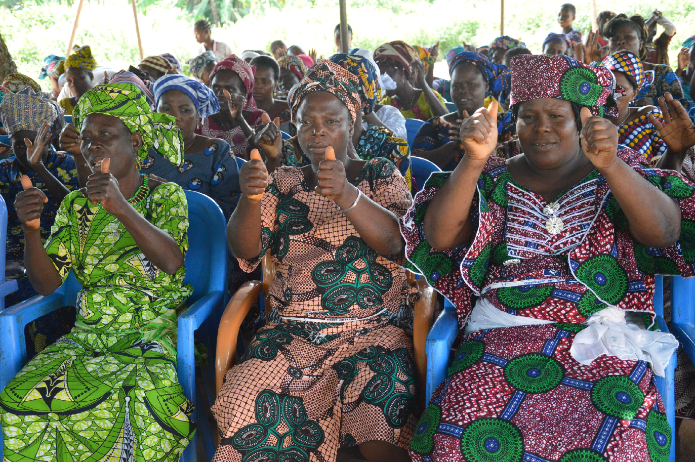 a group of women dressed in African Traditional attire, all giving the "thumbs up" signal